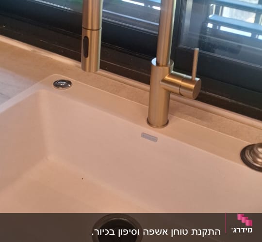 ברז זהב וכיור במטבח עם חלון ברקע